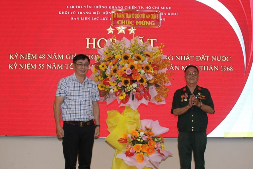 刘牛（右）代表市华运武装力量联络组接受第五郡越南祖国阵线委员会赠送的花篮。