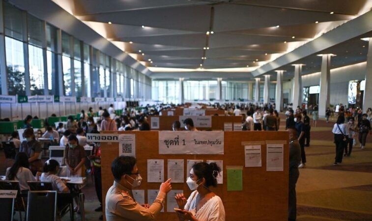5月7日，在5月14日大选前一周，一名选民（前右）在曼谷一家购物中心内的投票站提前投票，询问投票方向。（图：AFP）