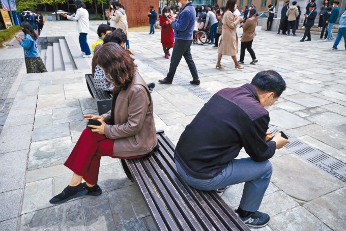 首尔上班族午膳时间在街上看手机。（图：互联网）