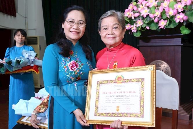 市人民议会主席阮氏丽向阮氏明红同志颁授60年党龄纪念章。（图：市党部新闻网）