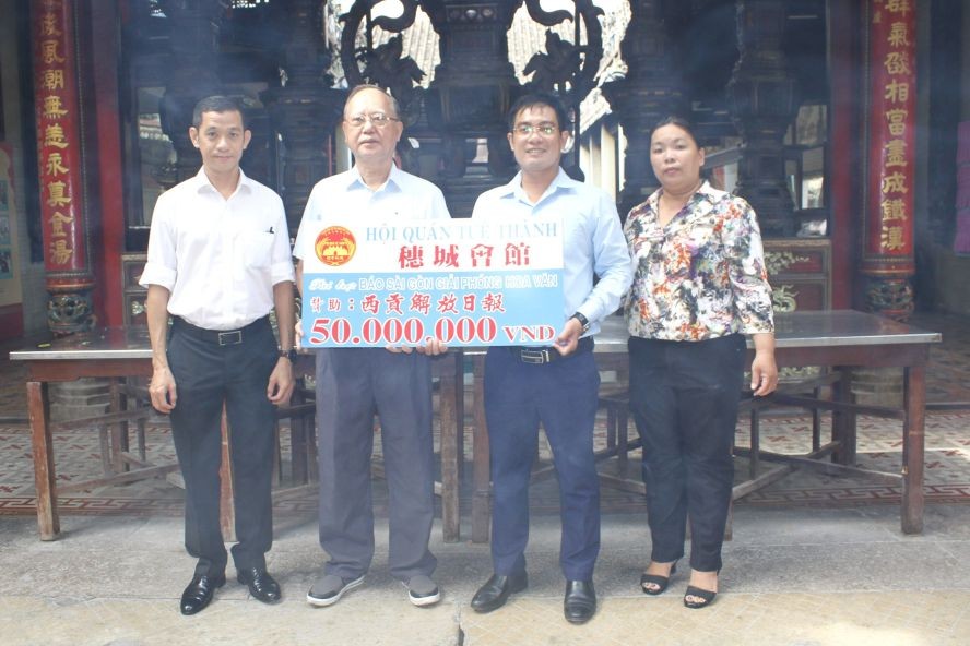 穗城会馆理事长卢耀南（左二）向本报编委文忠孝（右二）移交5000万元赠款。