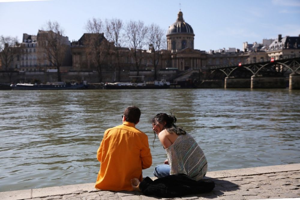 2021年3月24日，一对情侣在法国巴黎塞纳河畔晒太阳。（图：新华社）