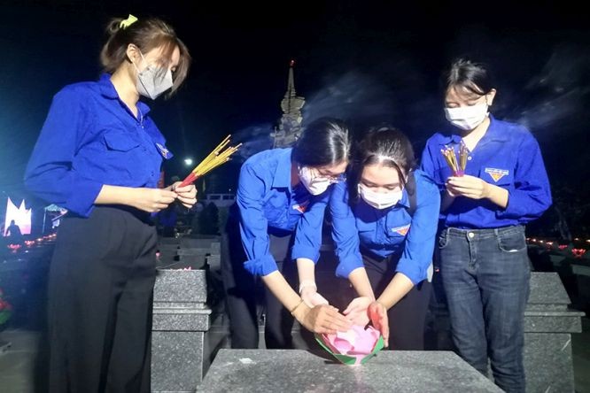 共青团员们在烈士陵园的英雄烈士坟墓上点燃蜡烛并上香表达敬意。（图：BTV）