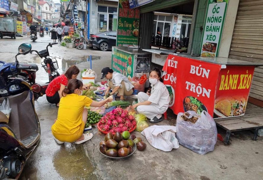 河内北升龙工业区的2名女工人在街旁摆卖果蔬以求多赚点额外收入。（图：XM）