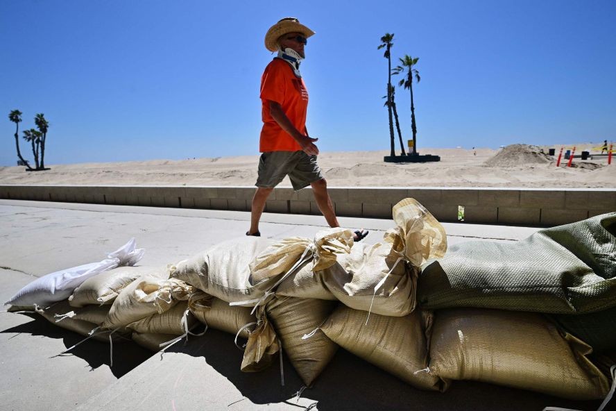 当地时间2023年8月18日，美国加州海豹滩，一名男子经过用来保护海滨房屋的沙袋，这是为防御飓风希拉里做准备。（图：AFP）