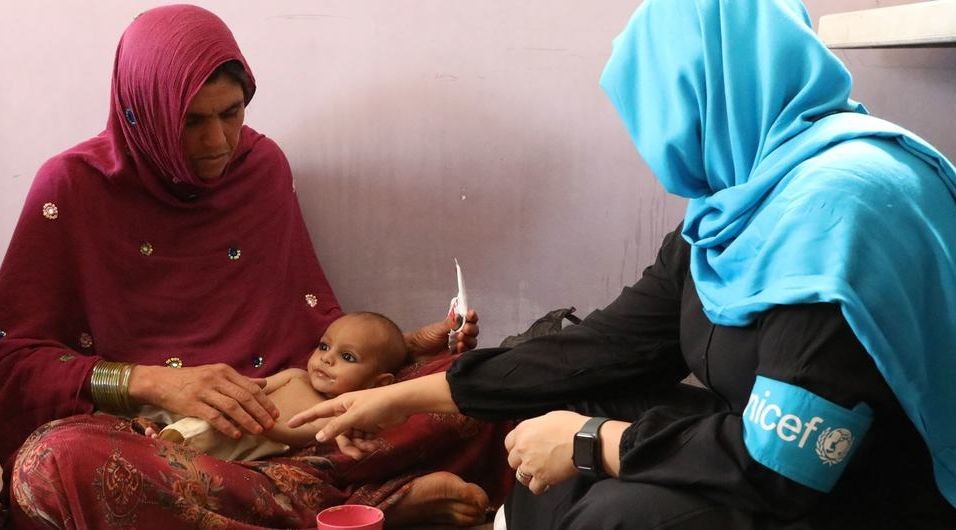 在阿富汗首都喀布尔，一名卫生工作者上门为一名营养不良的小孩看诊。（图：UNICEF）