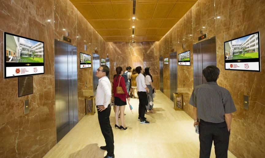 人们在等候电梯时观看楼宇电梯视频广告。