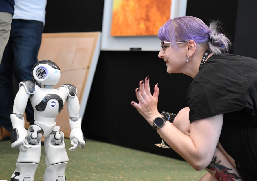 2023年7月7日，在瑞士日内瓦“人工智能造福人类全球峰会”上，一名参会者与机器人互动。（图：新华社）