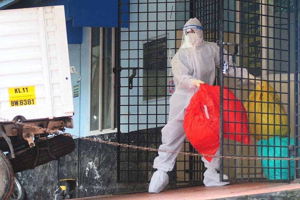 当地时间9月16日，印度喀拉拉邦，一名穿着防护装备的卫生工作者正在处理尼帕病毒隔离中心的垃圾。（图：互联网）