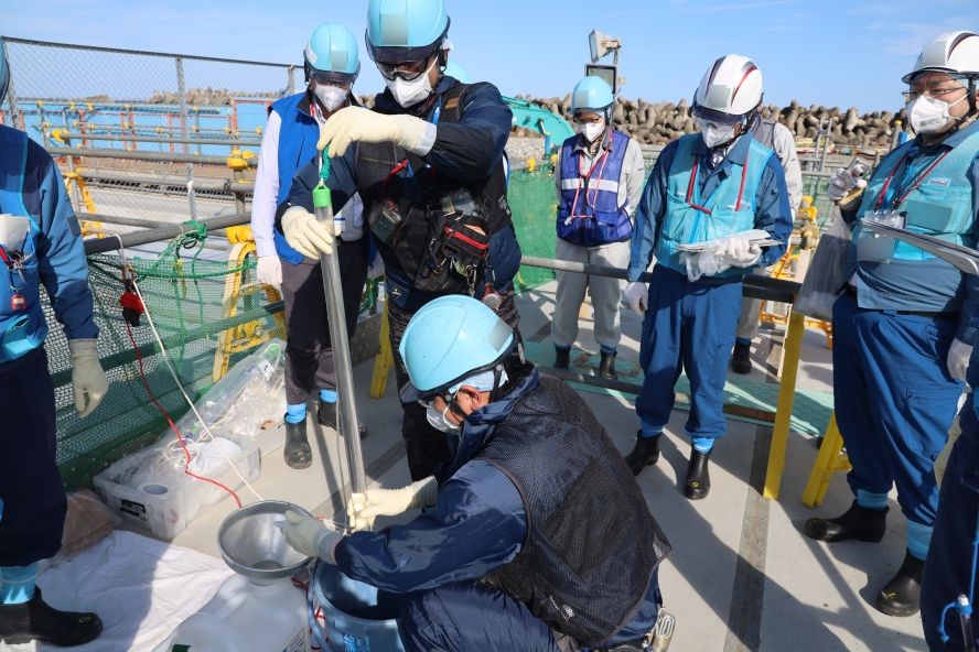 10月3日，东电工作人员在第二轮处理水排海作业启动前，对上游储水池的水进行取样。（图：AFP）