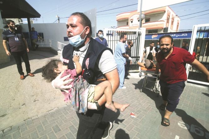 23日，在加沙地带南部城市拉法，人们将伤者送往医院。（图：新华社）