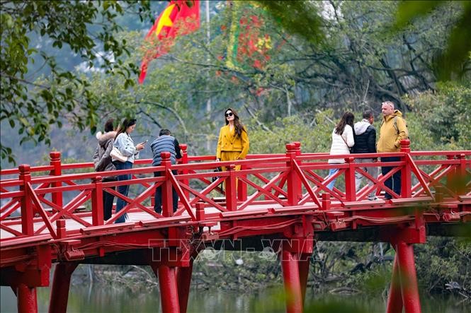 游客在河内市栖旭桥上观赏风景并拍照留念。（图：越通社）