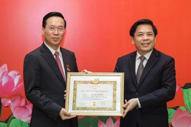 阮文体同志代表中央机关党委常务处向国家主席武文赏（左）颁授30年党龄纪念章。（图：国家主席办公厅）