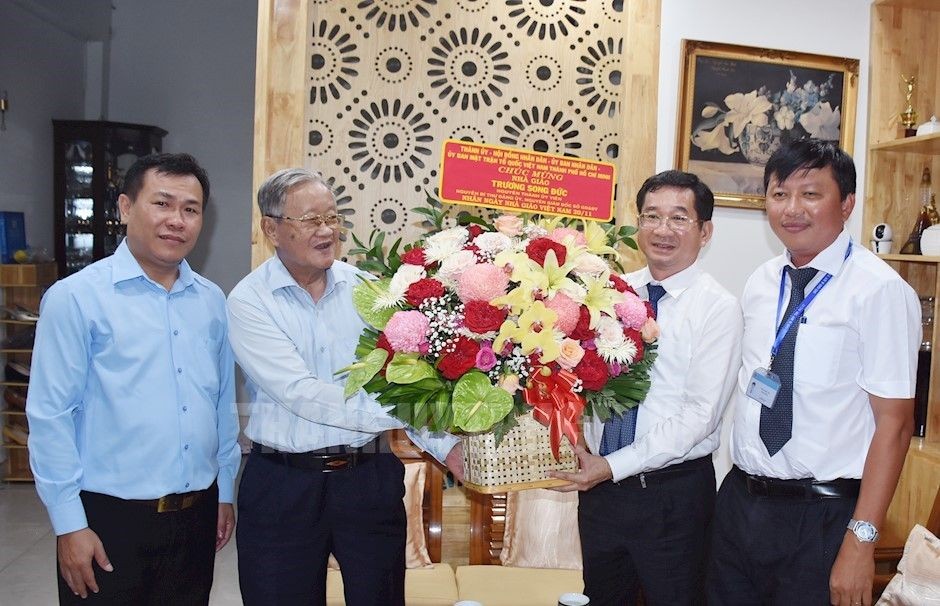市委检查委员会主任杨玉海（右二）向市教育与培训厅原厅长张双德教师赠送鲜花。（图：市党部新闻网）