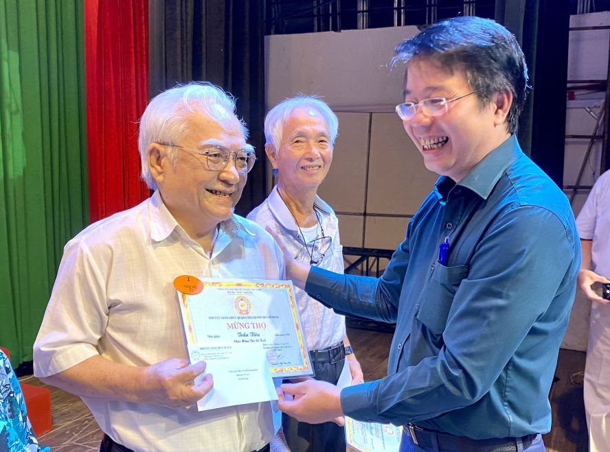 第六郡人委会副主席黎清平向两位85岁华人教师陈标（左一）和黄金城（左二）祝寿。