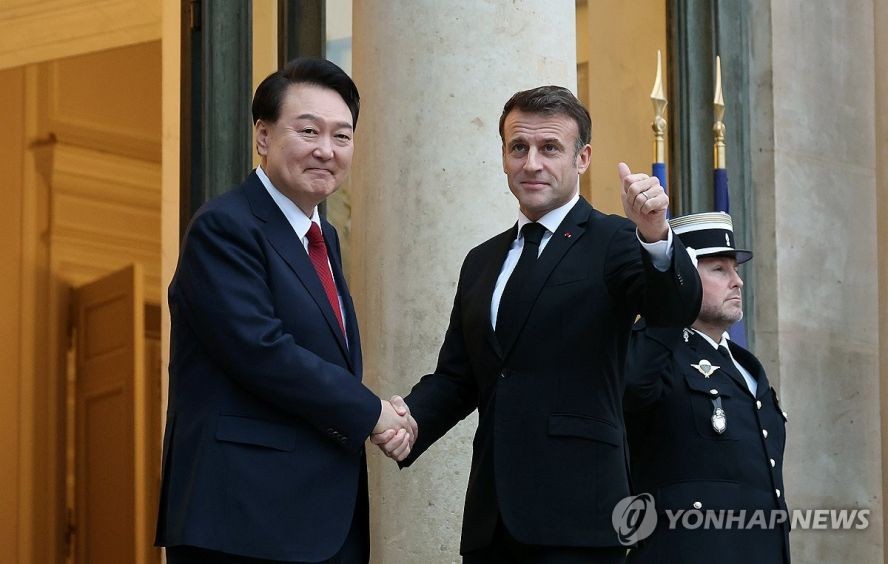 当地时间11月24日，在巴黎爱丽舍宫，韩国总统尹锡悦（左）与法国总统马克龙握手致意。（图：韩联社）