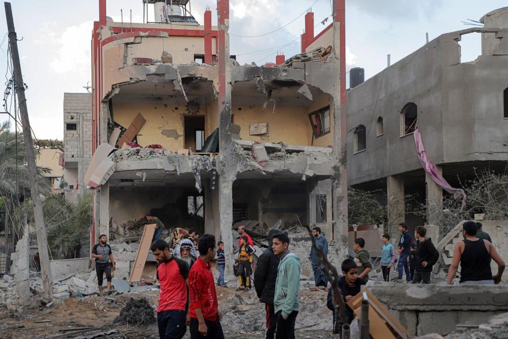 12月1日，人们聚集在加沙地带南部城市汗尤尼斯一处被炸的建筑前。巴勒斯坦加沙地带卫生部门1日晚发表声明说，以色列军队当天恢复对加沙地带空袭，已造成至少178人死亡、589人受伤。（图：新华社）