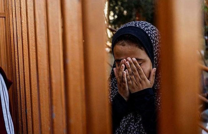 以哈冲突造成大量人员伤亡。图为12月9日，一名巴勒斯坦女童出席一场葬礼时忍不住掩面痛哭。（图：路透社） 