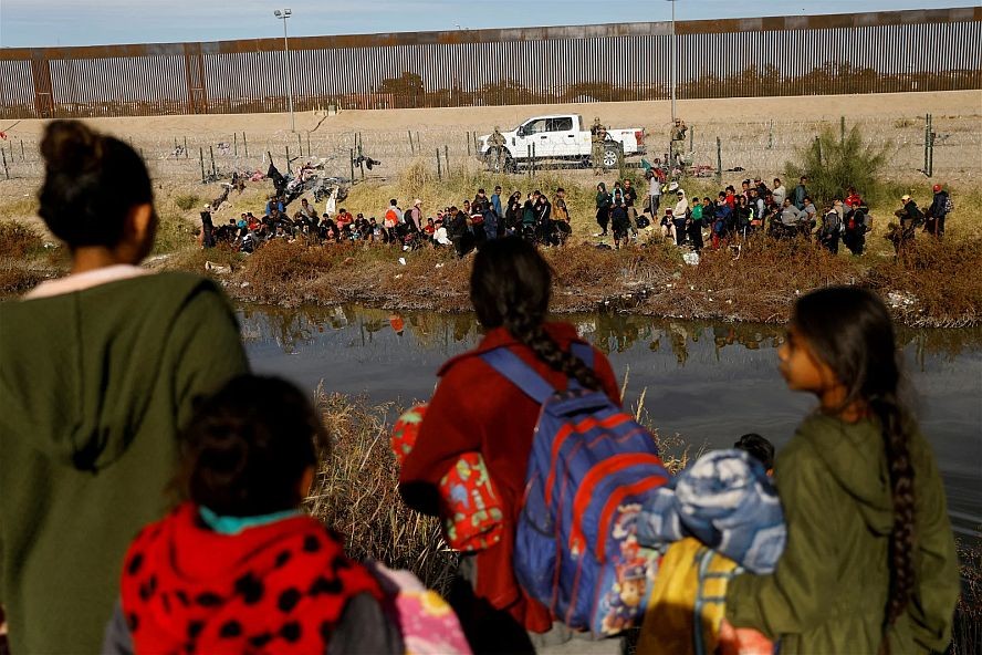 大批移民涉水穿过格兰德河后，留在河畔等待，想要伺机入境美国，得州国民警卫队在篱笆后戒备。（图：路透社）