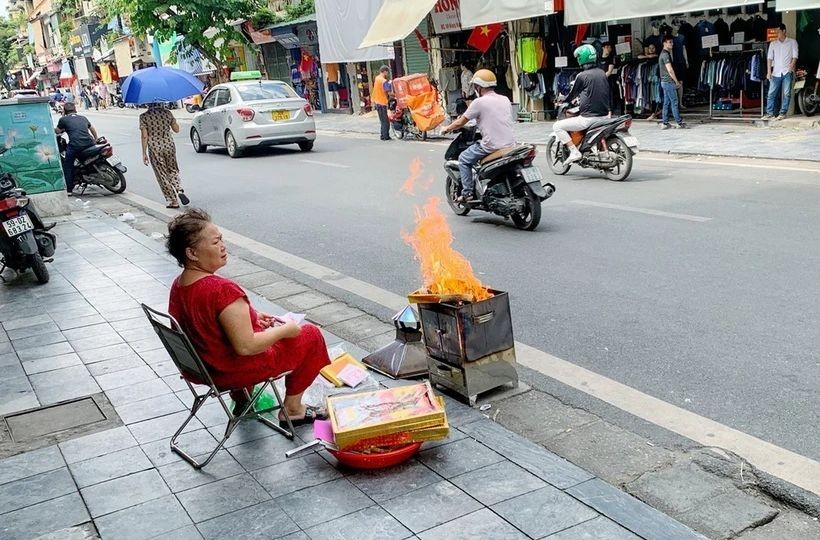 一名老妇在桃街旁焚烧冥纸。（图：越通社）