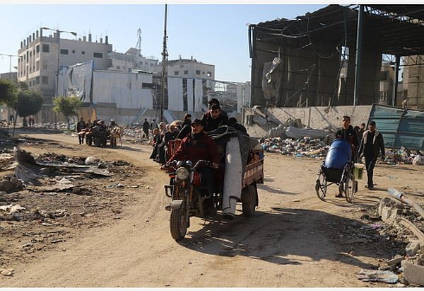 人们经过加沙城受损的建筑。（图：新华社）
