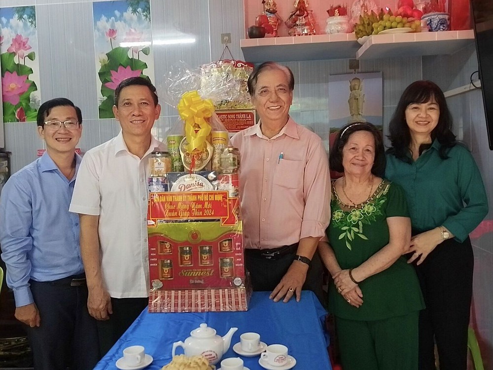 市委民运处副主任陈春田（左二）和陪同团向朱杞文赠送贺年礼物。
