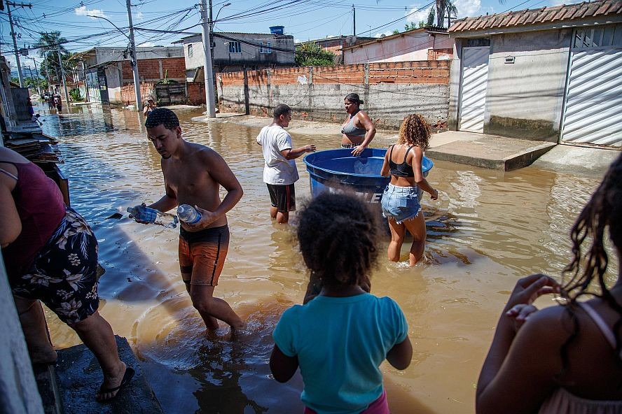 2024年1月16日，在巴西里约州卡希亚斯公爵城，志愿者为受灾居民送饮用水。巴西里约热内卢州本月13日晚开始的暴雨导致里约市北区和里约州内陆多座城市受灾严重。（图：新华社）
