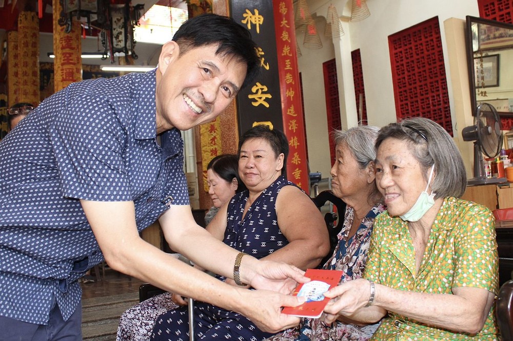 海南会馆理事长林明辉向乡亲派发贺年利是。
