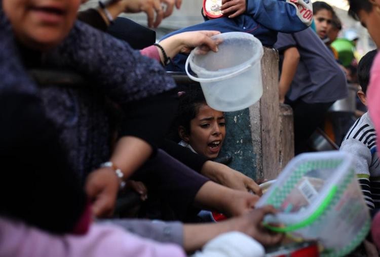 3月14日，人们在加沙地带南部城市拉法领取救济食物。（图：新华社）