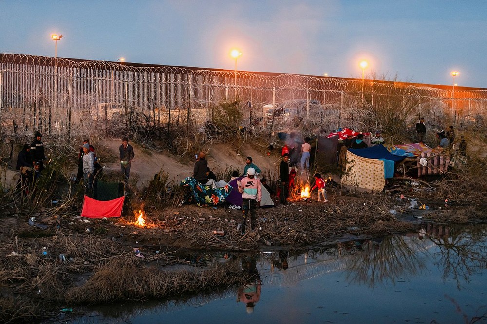 图为19日，一群移民在格兰德河美国一侧的边境墙附近露营。（图：互联网）