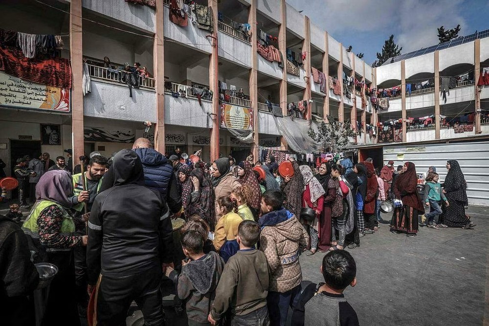 图为2月19日，流离失所的巴勒斯坦平民在加沙南部拉法市的一所政府学校内，排队领取食物。（图：AFP） 