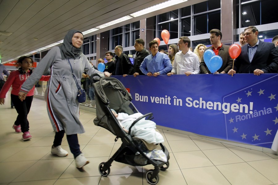 3月31日，在罗马尼亚首都布加勒斯特附近的亨利·科安达国际机场，旅客走过一处写有“欢迎加入申根”标语的牌子。（图：新华社）