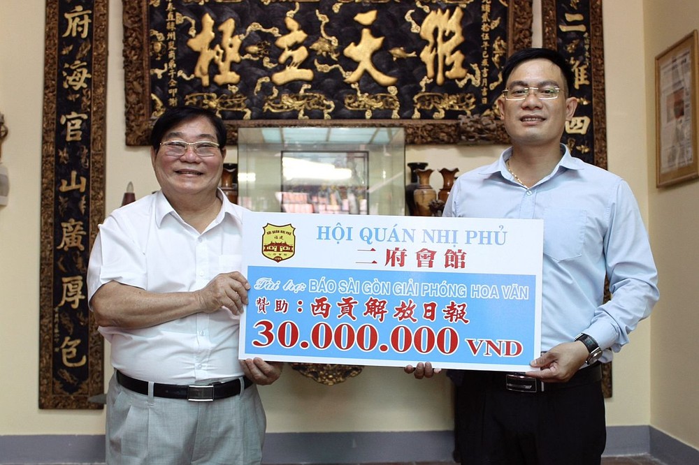 二府会馆理事长彭伟强（左）把3000万元赠报经费交给本报编委文忠孝。