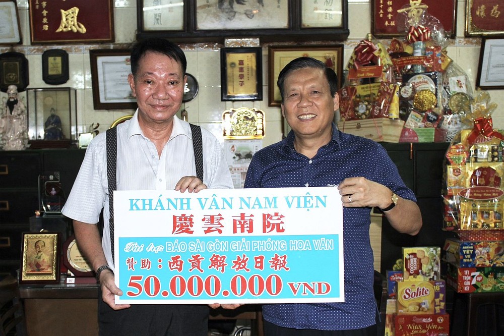 庆云南院住持周华邦（左）把赠款交给《西贡解放报》副总编辑、本报主编阮玉英(红蓝)。