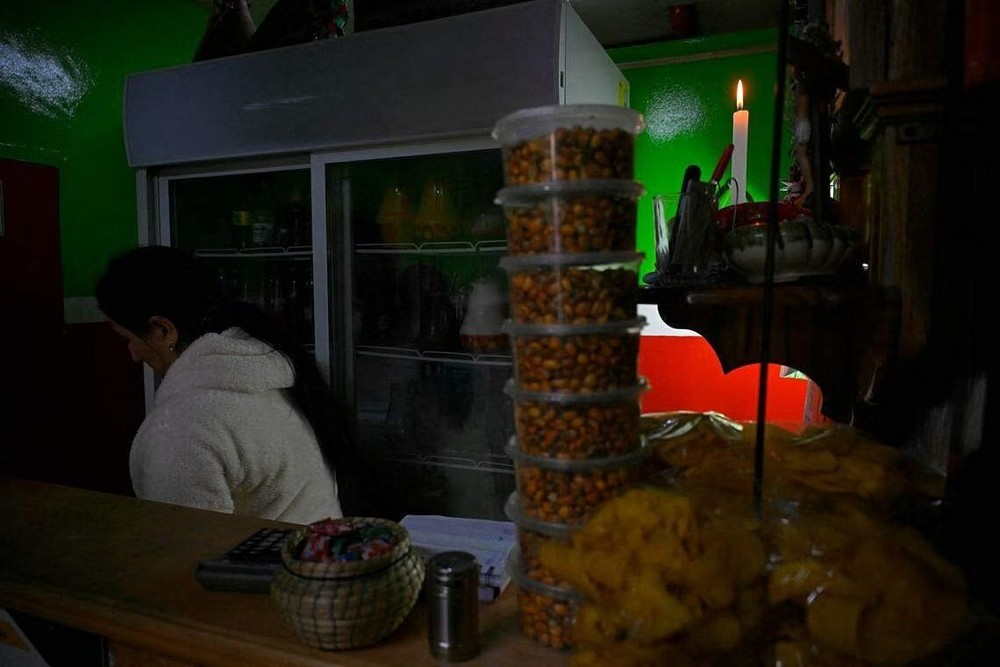 基多4月18日起每天分区域停电八小时。图为一名妇女站在黑暗的商店里。（图：AFP）