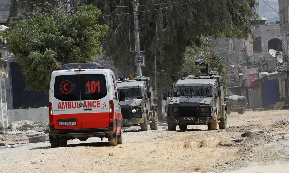 20日，在约旦河西岸城市图勒凯尔姆，以色列军车阻止救护车进入冲突现场。（图：新华社）