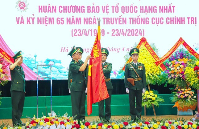 边防部队政委阮英俊中将为边防部队传统旗帜上佩挂一等捍卫祖国勋章。（图：阮明）