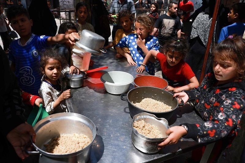 2024年4月19日，在加沙地带拉法，流离失所的巴勒斯坦儿童领取食物。（图：新华社/AFP）