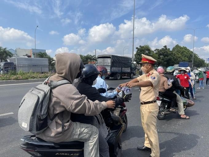 交警站在1号国道路旁向回乡度假的劳动者和学生赠送矿泉水。（图：秋红）