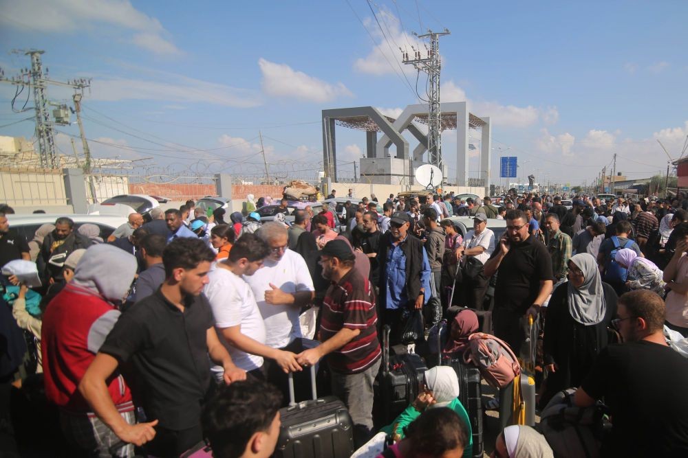 人们在加沙地带南部的拉法口岸前等待撤离加沙地带。（图：新华社）