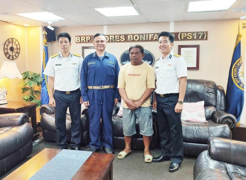 第四区海军司令部干部（白衬衫）将遇险渔民（右二）移交给菲律宾巡逻舰时合影留念。（图：越通社）