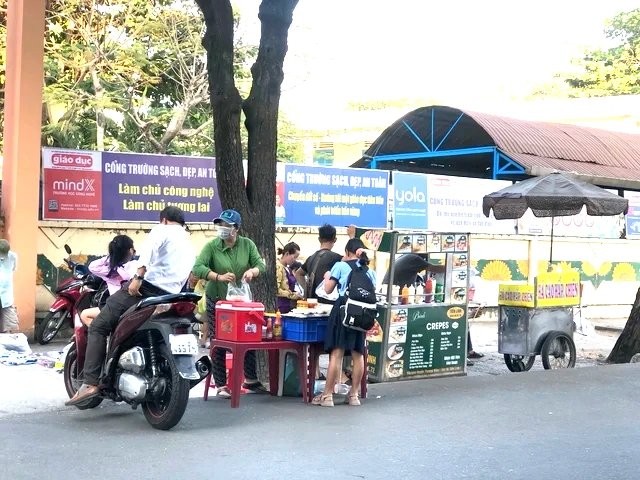 学生在学校门口的肩挑小贩购买食品。