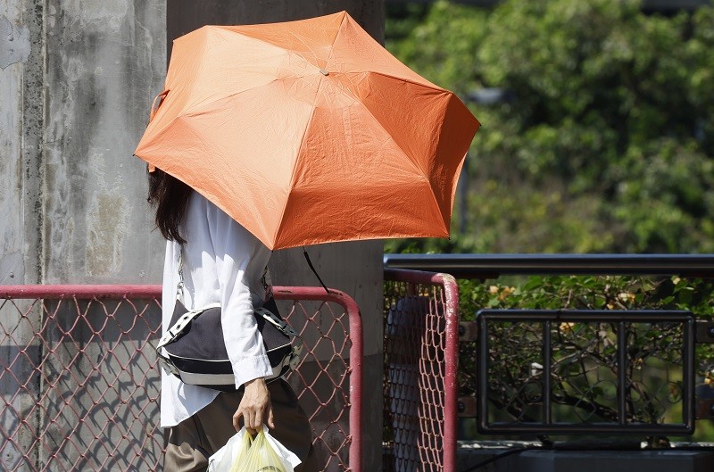 4月24日，在泰国曼谷，行人撑伞遮挡阳光。 （图：新华社/欧新）