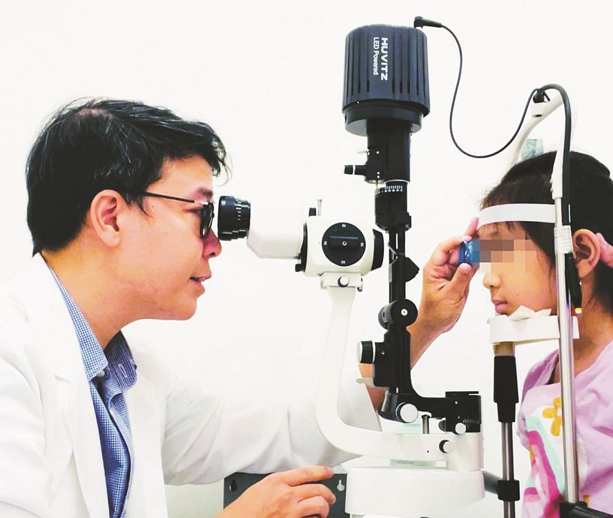 陈廷明辉博士、医生为一名病童检查视力。