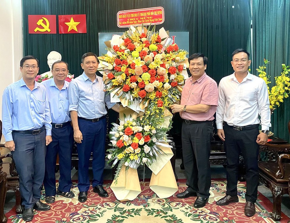 市委民运处副主任陈春田（左三）向本报主编阮玉英（右二）赠送鲜花祝贺。