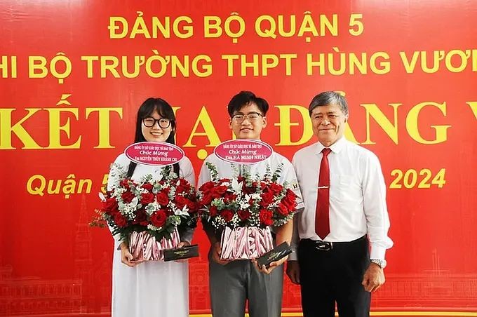 市教育与培训厅厅长阮文孝（右一）向雄王高中学校的两名新党员赠送鲜花祝贺。（图：阮兴）