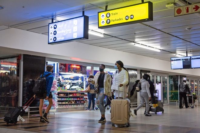 在南非约翰内斯堡坦博国际机场，人们戴口罩从店面旁走过。（图：新华社）