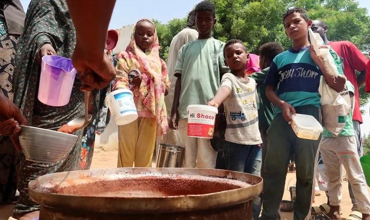 苏丹民众排队等候分发食物和用水。（图：THE GUARDIAN）