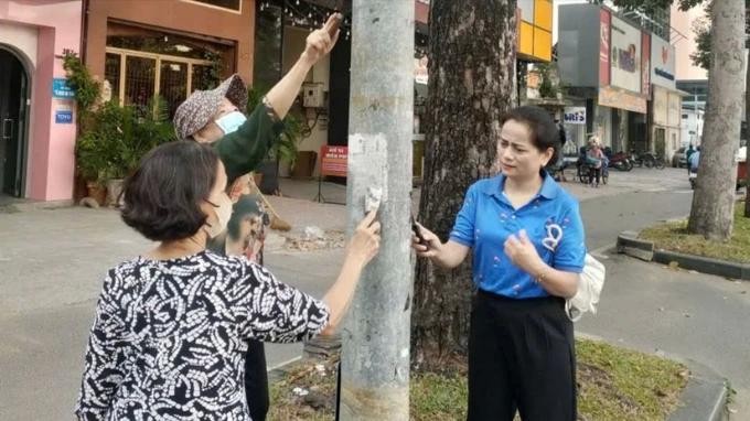 市民与职能力量协力清除路灯柱上的违规广告产。（图：志石）