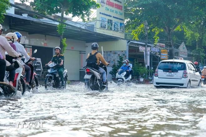 图为9月中旬潮汛期间，芹苴市多条街道遭受严重淹水，人们出行困难。（图：越通社）